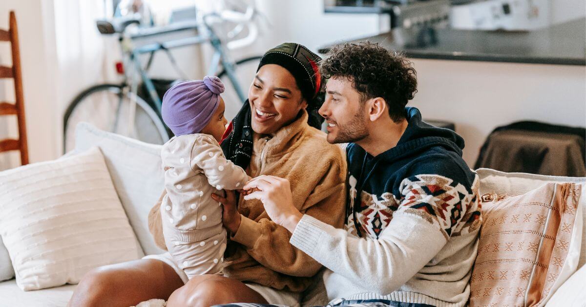 Two parents smiling at a baby